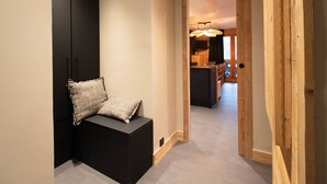 A hallway with a black bench, a wooden door frame, and a view into a kitchen area. - 5-room duplex for 10 guests with balcony, Hameau de la Forêt (Valmorel)
