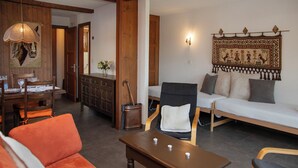 A cozy living room with a wooden dining table, orange sofa, and a wooden bench. - Pigne 1 by Interhome (Verbier)