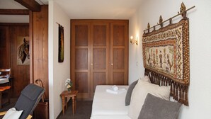 A cozy room with a bed, a chair, a small table with a vase of flowers, and a wooden wardrobe. - Pigne 1 by Interhome (Verbier)