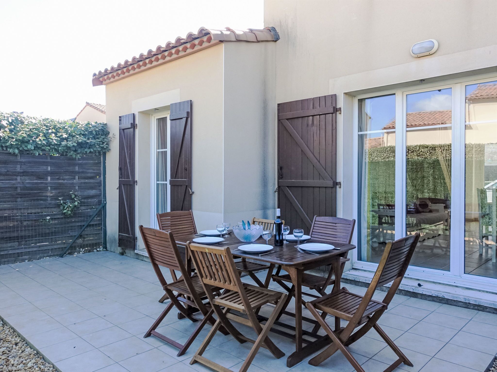 Eine Terrasse im Freien mit einem Tisch für vier Personen, umgeben von Holzstühlen.
