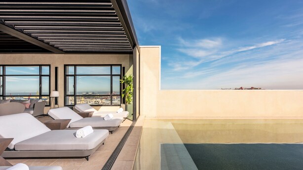 Terraza con sillones, piscina y vistas a la ciudad.