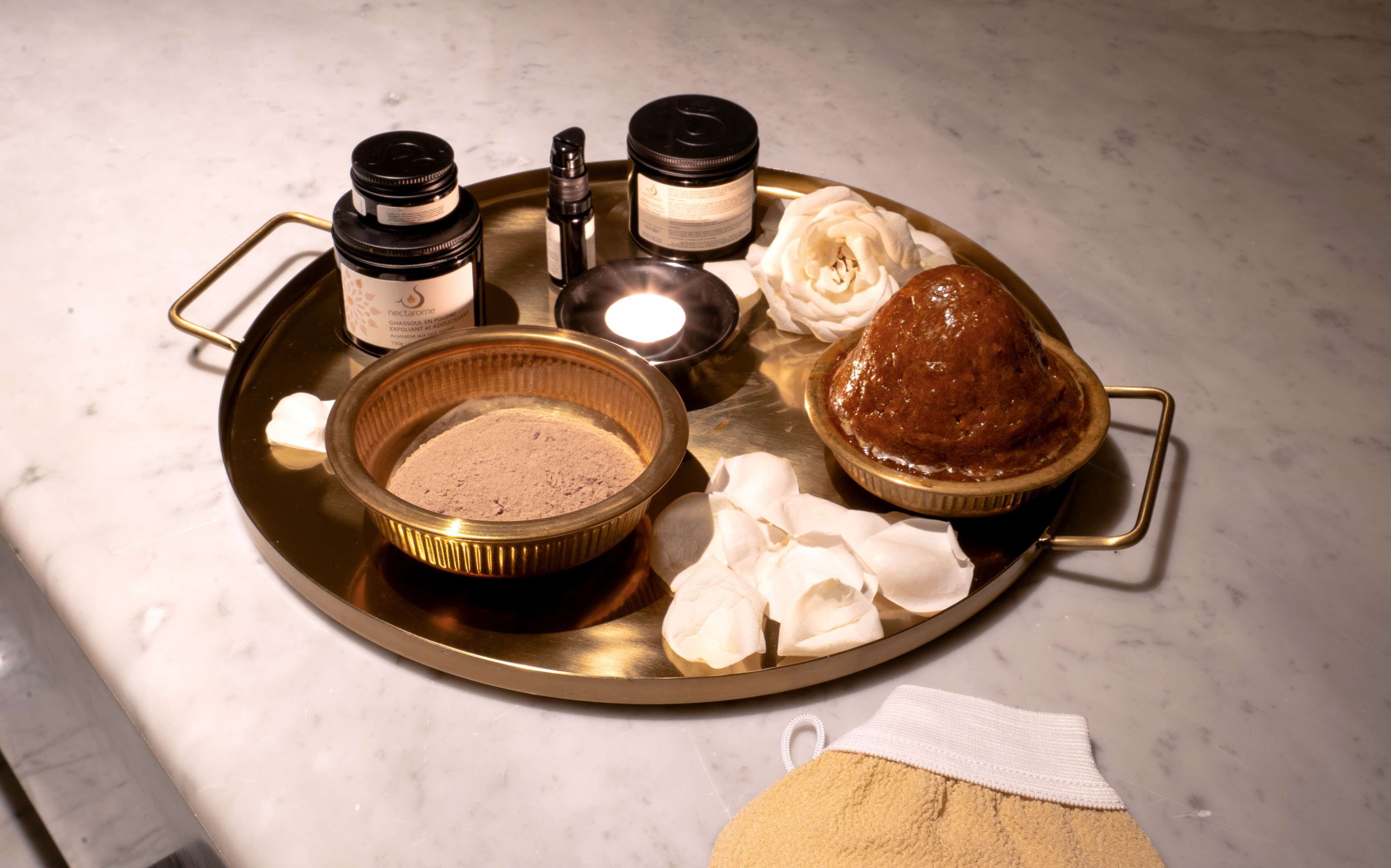 A tray with various items including a bowl of powder, a jar, a candle, and a baked item.
