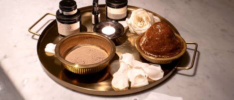 A tray with various items including a bowl of powder, a jar, a candle, and a baked item.