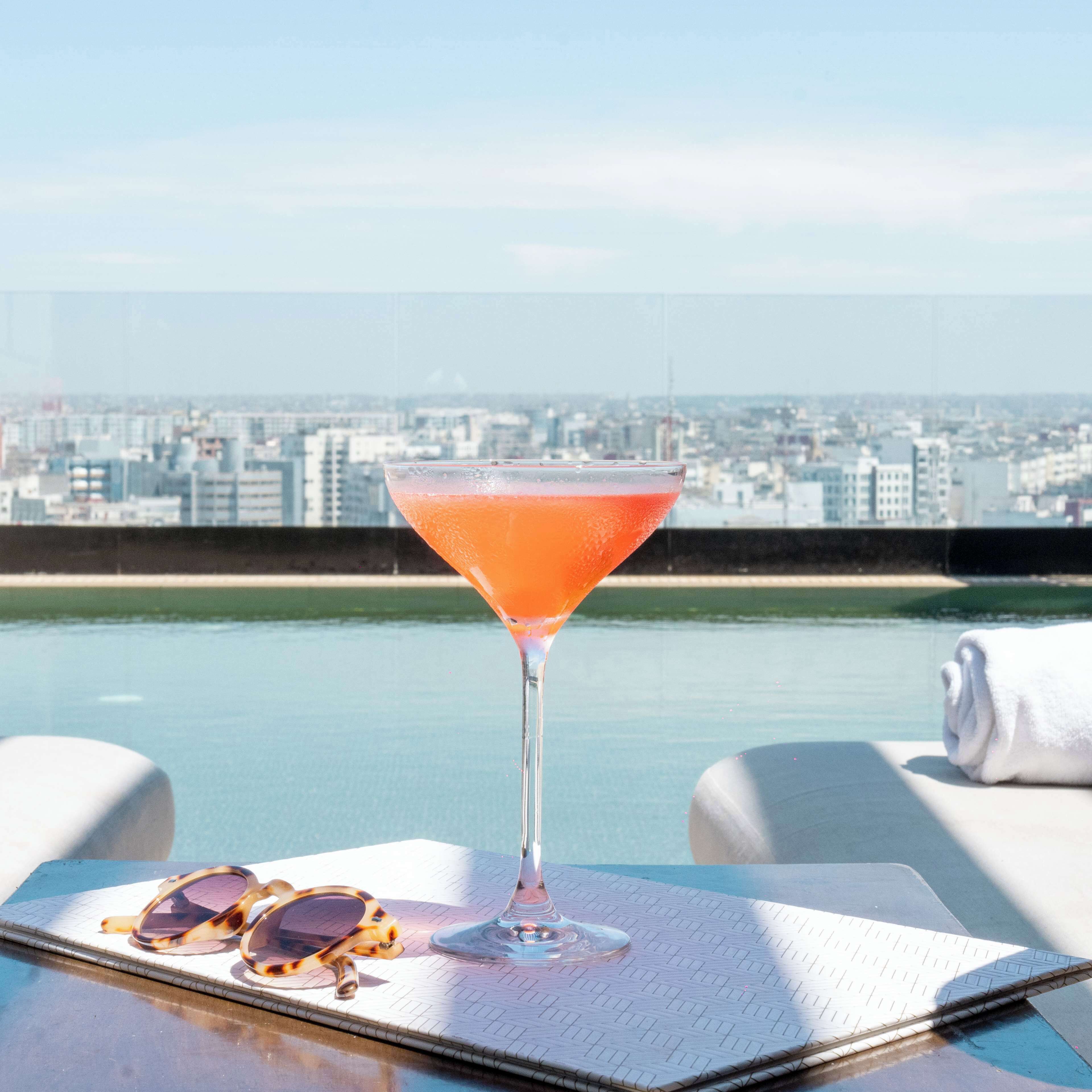 A cocktail on a table with a city view in the background.