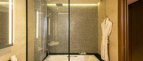 Un baño moderno con una bañera grande, una ducha con cerramiento de vidrio y una pared con mosaico de azulejos.