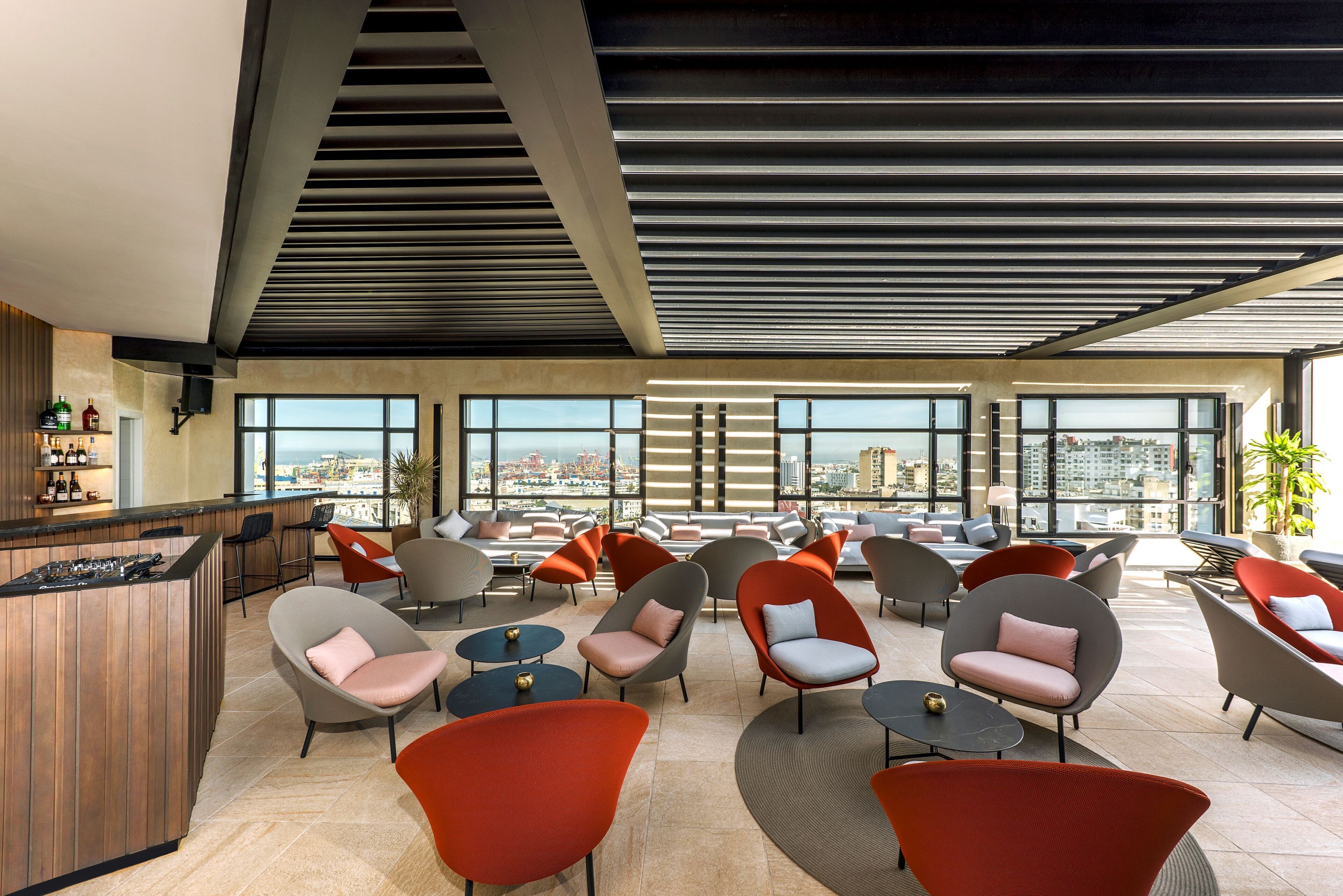 A modern lounge area with multiple seating options, a bar, and large windows offering city views.