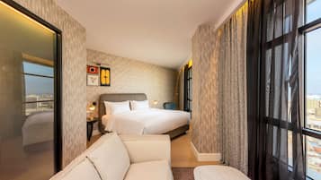 Une chambre d’hôtel avec un grand lit, un canapé, une table de chevet et une fenêtre avec des rideaux.