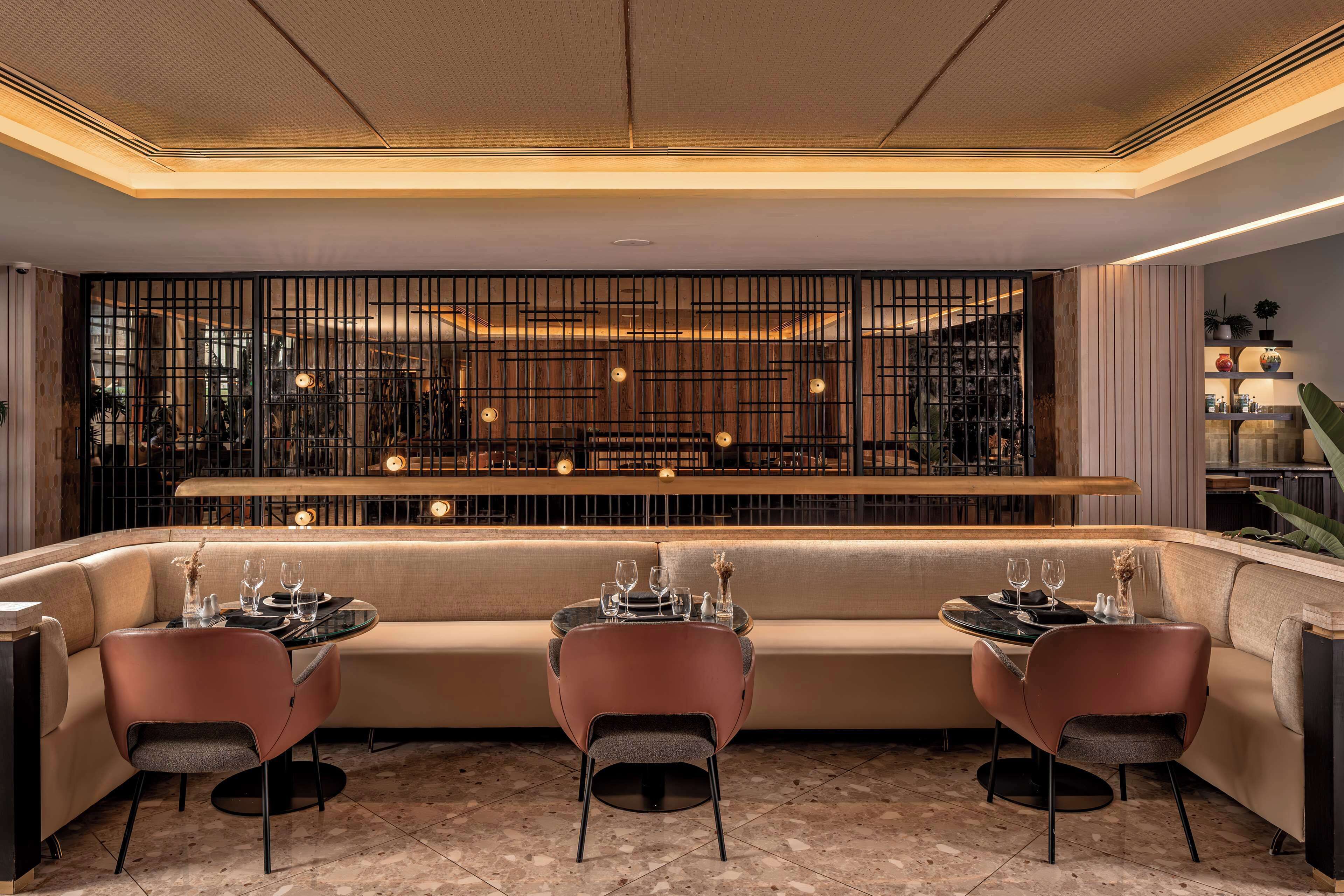 Un espace repas moderne comprenant un canapé et des fauteuils, un comptoir de bar et un élément de séparation décoratif.