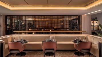 Un espace repas moderne comprenant un canapé et des fauteuils, un comptoir de bar et un élément de séparation décoratif.