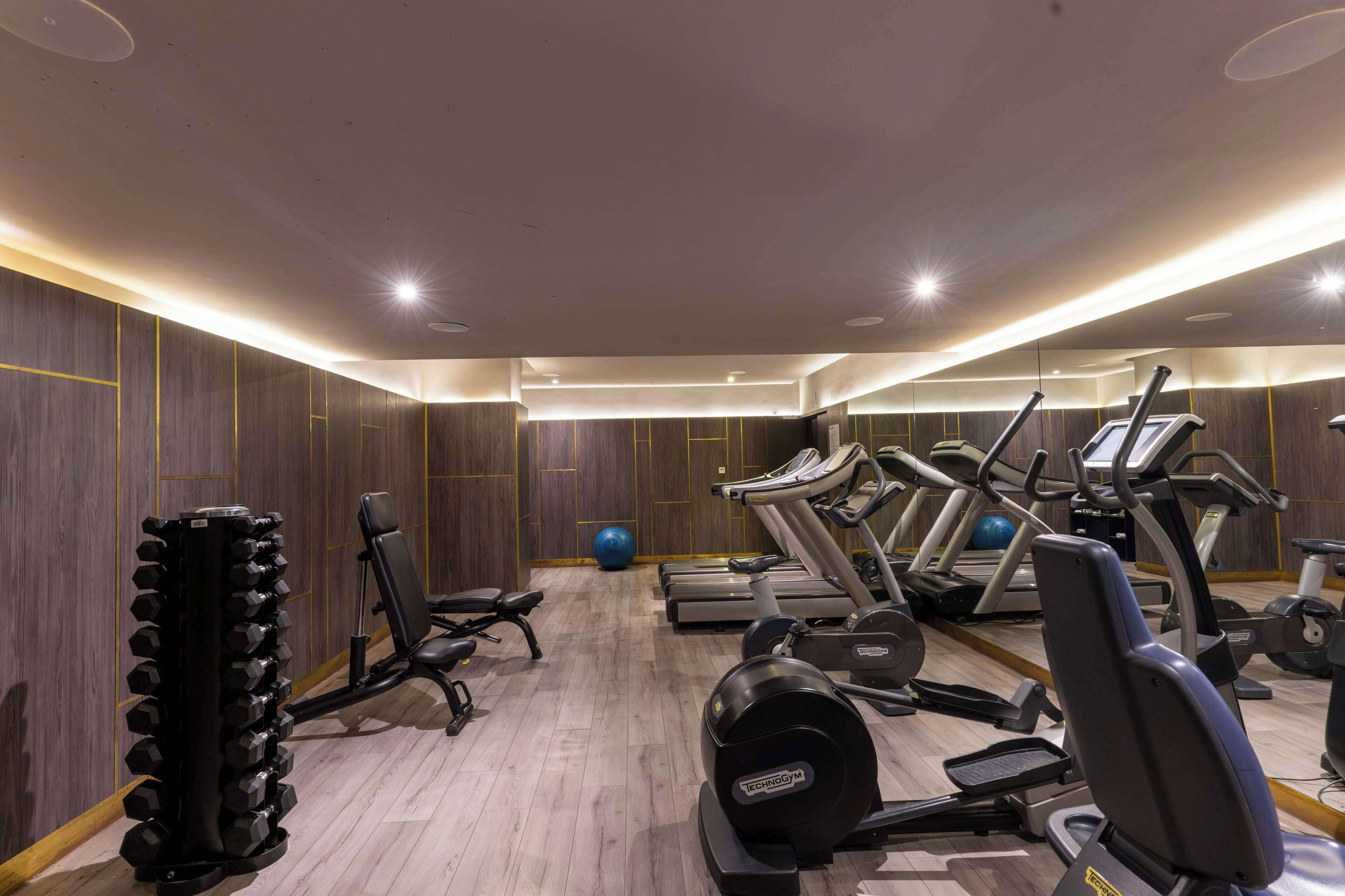 Een fitnessruimte met loopbanden, een roeimachine en een gewichtstapel.