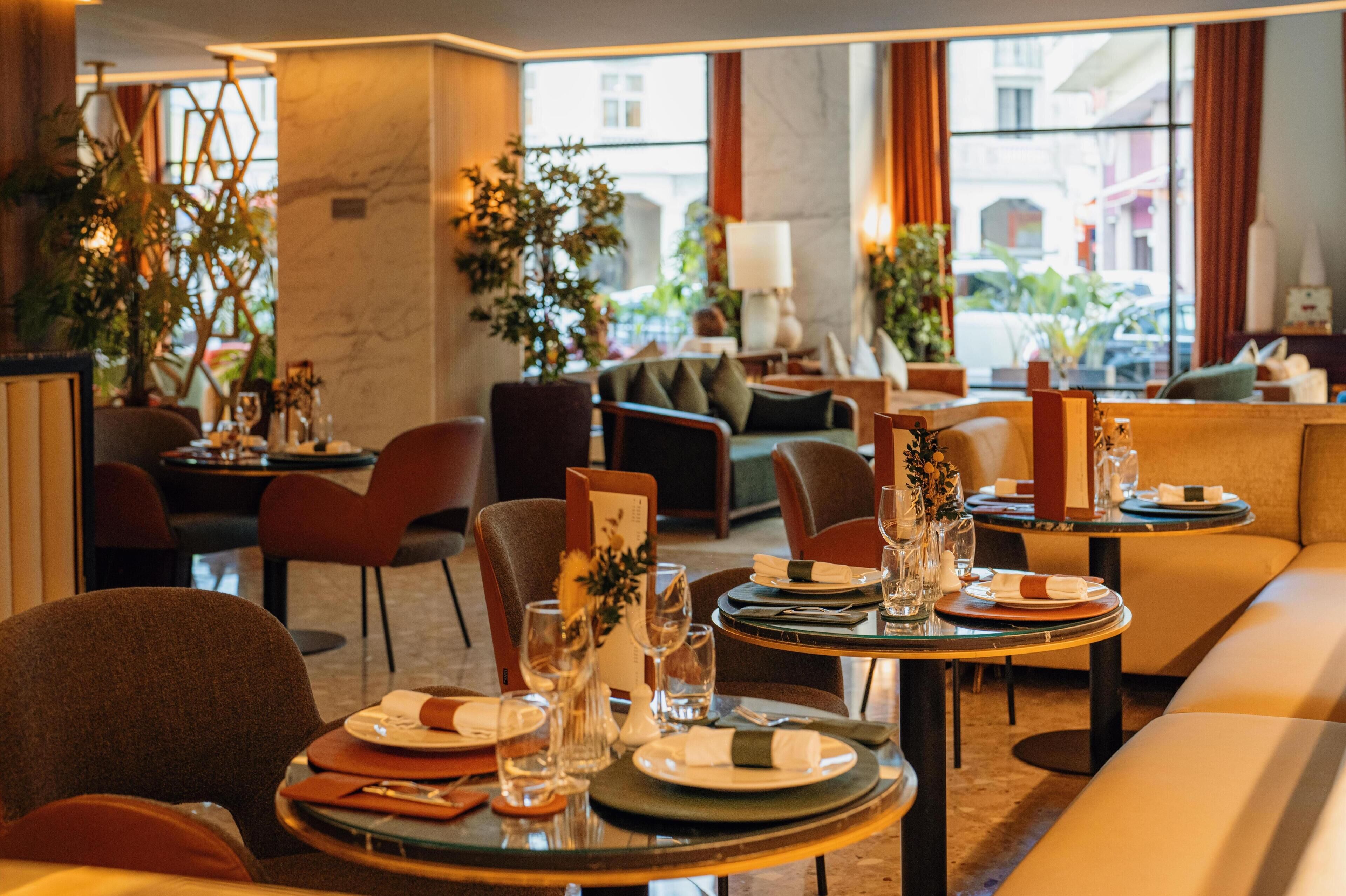 A well-lit dining area with tables set for two, featuring clear glassware and neatly arranged plates.