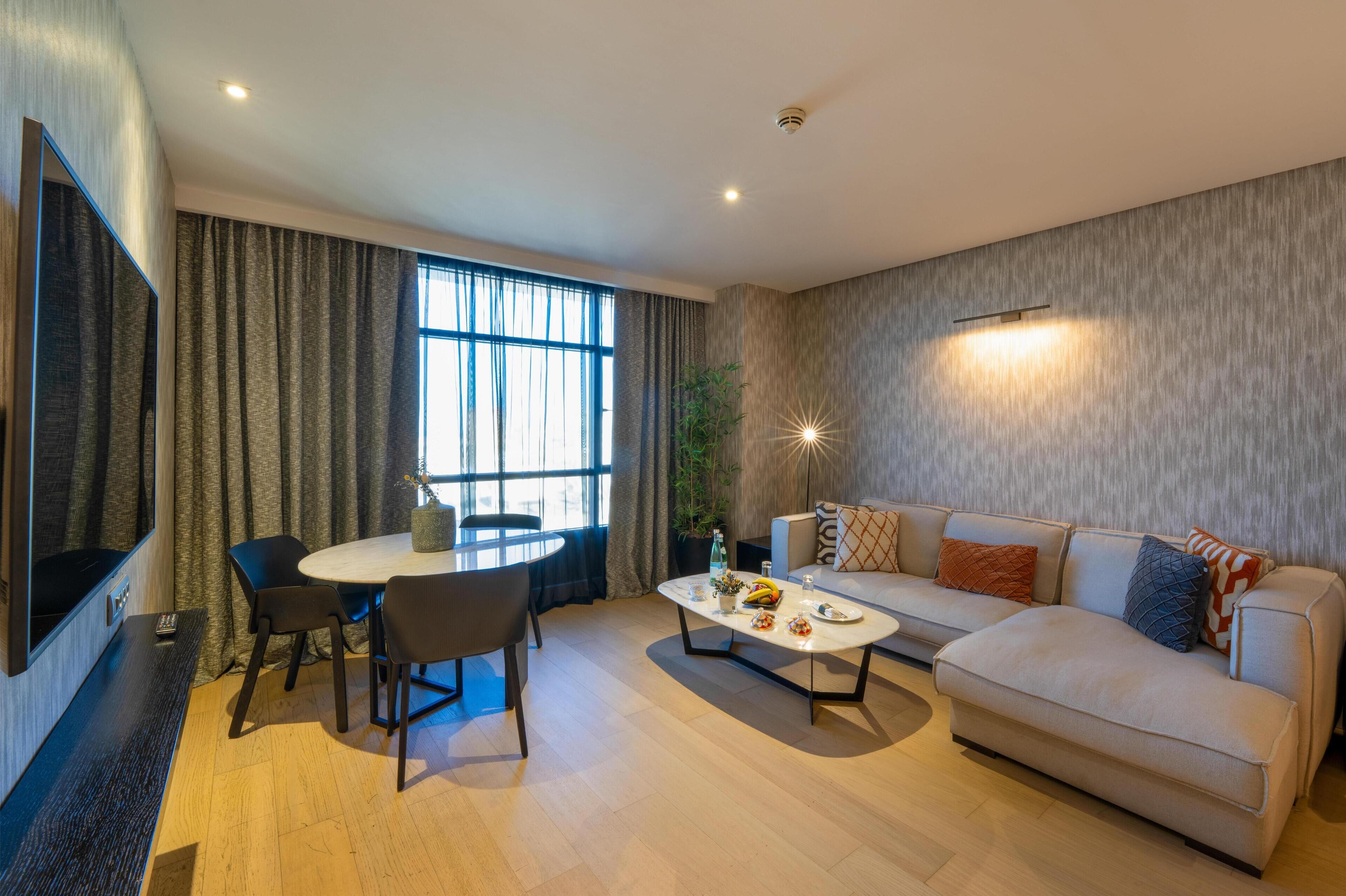 A modern living room with a sofa, coffee table, and dining area.