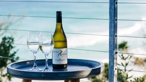 Une table avec une bouteille de vin et deux verres, placée sur un balcon donnant sur un paysage magnifique.
