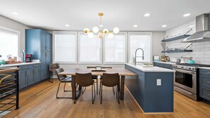 Una cocina moderna con una isla central, suelo de madera y una araña.