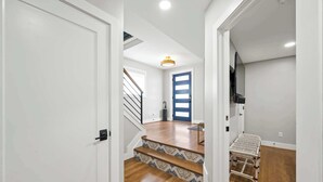 Una escalera con peldaños estampados que lleva a un cuarto con una puerta azul y un televisor montado en la pared.