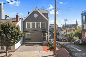 A two-story house with a front porch, a small garden, and a visible street view.