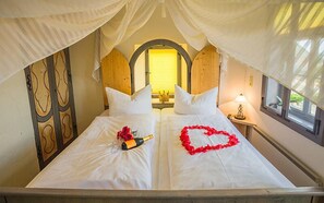 A double bed with a heart-shaped decoration and a bottle on the bed.