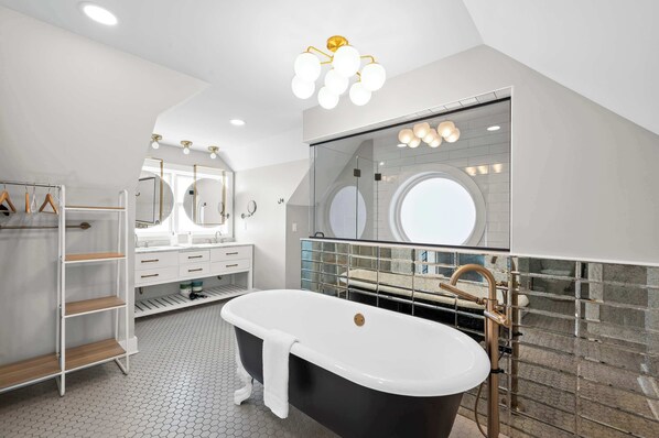 Un baño moderno con una bañera independiente, un tocador con un espejo grande y una zona de ducha con mampara de vidrio.