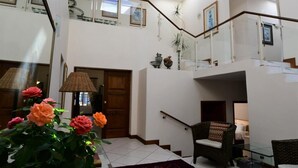 A spacious interior with a staircase, a seating area with a chair, and a potted plant. - Highgrove Guesthouse (Sandton)