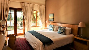 A hotel room with a large bed, a desk, and a view of the outdoors through a glass door. - Highgrove Guesthouse (Sandton)