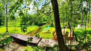 A wooden deck with a view of a stream and a picnic area with benches and chairs. - Plitvice Streaming (Plitvicka Jezera)