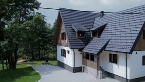A modern house with a sloped roof, a wooden deck, and a stone pathway leading to the entrance. - Plitvice Streaming (Plitvicka Jezera)