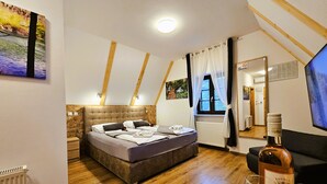 A bedroom with a bed, wooden floor, a window with curtains, a mirror, and a bottle of wine. - Plitvice Streaming (Plitvicka Jezera)