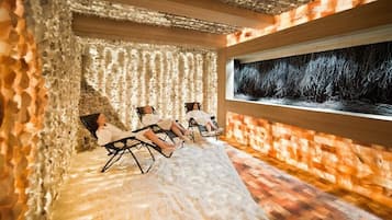 Relax in a serene space with textured walls, reclining chairs, and a large window offering a forest view.