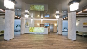 A spacious lobby with a reception desk, large columns, and a wooden floor. - Molo Resort Hotel (gmina Osiek)
