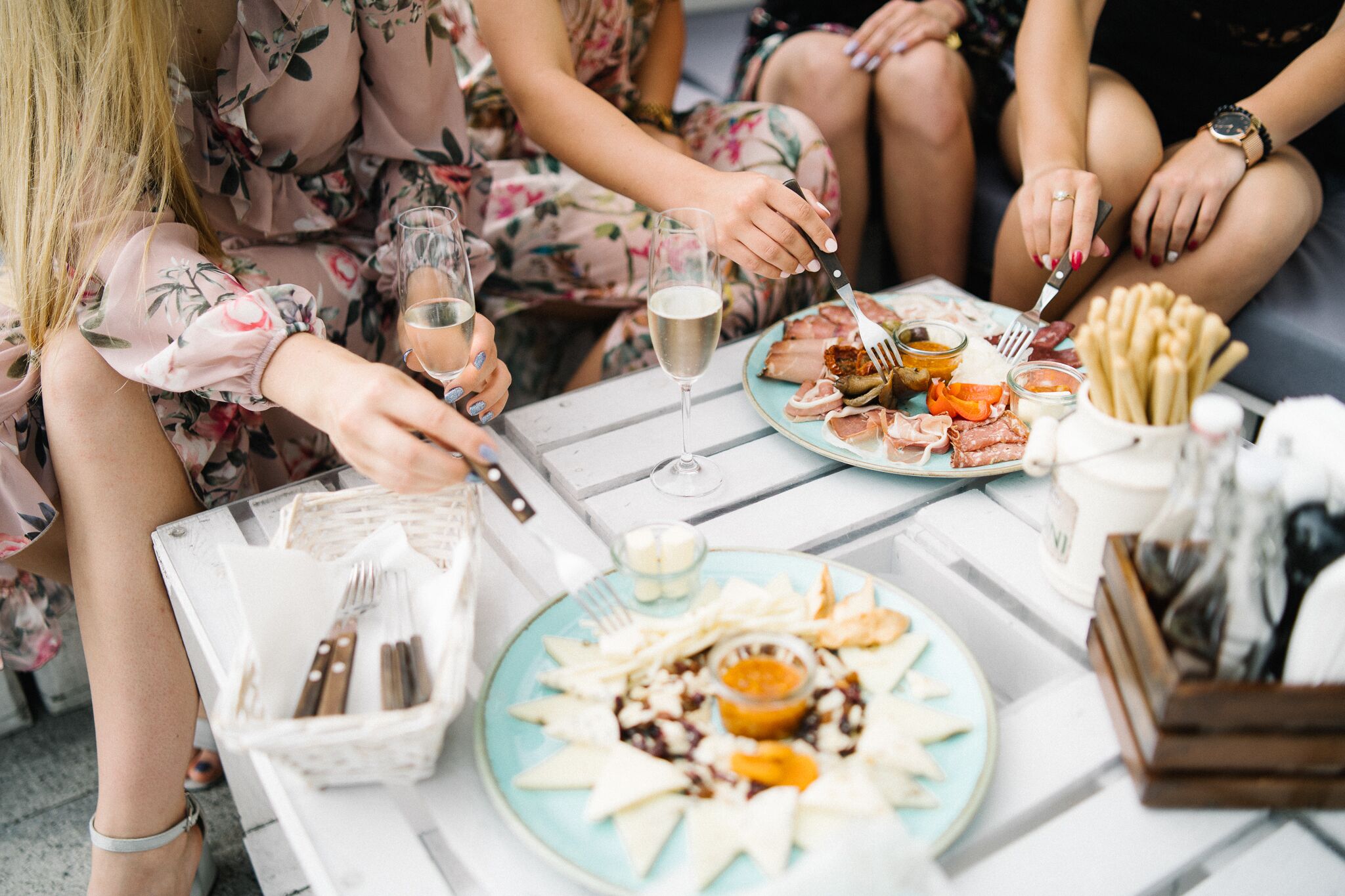 Un grupo de personas cenando en una mesa con platos de comida, copas de vino y cubiertos.
