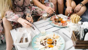 Un grupo de personas cenando en una mesa con platos de comida, copas de vino y cubiertos.