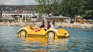 A yellow boat with four passengers on a calm body of water, surrounded by buildings and trees.