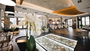 A spacious lobby with a central seating area, a glass display case with decorative items, and a staircase on the left. - Molo Resort Hotel (gmina Osiek)