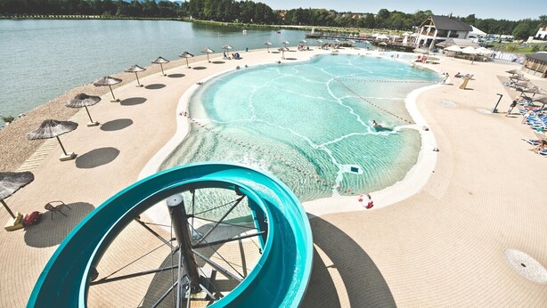 A water park with a large pool, slides, and beach areas with umbrellas. - Molo Resort Hotel (gmina Osiek)
