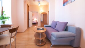 A modern living room with a sofa, a dining table with chairs, and a small side table.