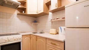 A kitchen with wooden cabinets, a built-in oven, a sink, and a refrigerator.