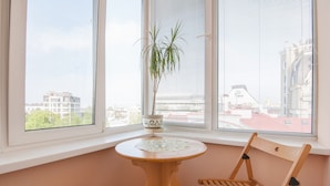 A room with a window, a wooden chair, a small table, and a potted plant.