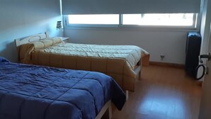 A room with two beds, a window, and a door with a handle. - Departamentos Balcarce (Balcarce)