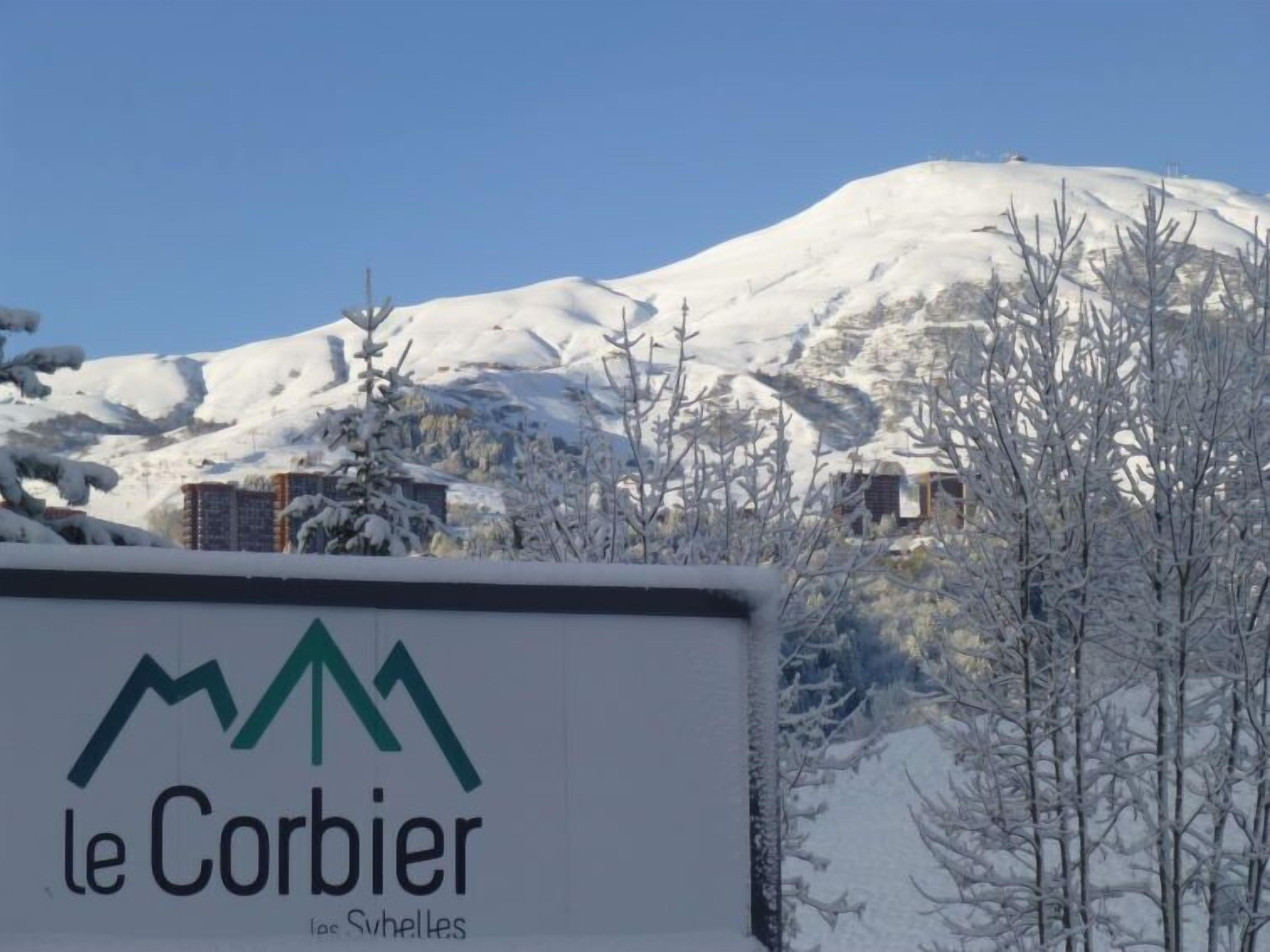 Une enseigne indiquant « Le Corbier », avec une montagne en arrière-plan.