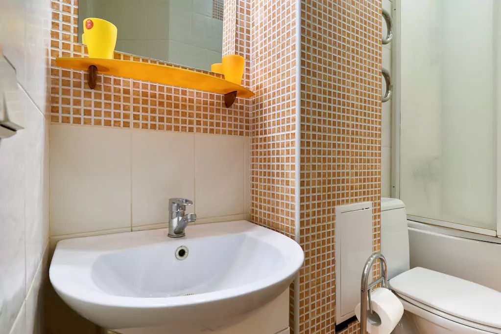 Un baño con lavamanos blanco, inodoro y zona de ducha.