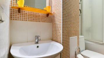 Un baño con lavamanos blanco, inodoro y zona de ducha.