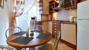 A compact kitchen with a dining table, chairs, a microwave, stove, and cabinets. - Home-Hotel Voloshskaya 51 (Kyiv)