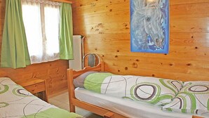 Une chambre dans un chalet en bois, avec deux lits, un radiateur et un tableau représentant un cheval.
