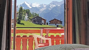 Une chambre avec vue sur des montagnes enneigées et une cabane en bois.