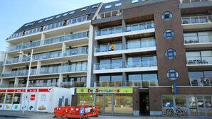 Ein mehrstöckiges Gebäude mit Balkonen, ein Laden mit Schaufenster und ein Fahrrad davor.