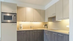 Eine moderne Küche mit integriertem Mikrowellenherd, einer Kaffeemaschine und dunklen Holzschränken.