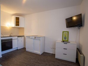 A compact kitchen with white cabinetry, a built-in oven, and a wall-mounted TV. - Côte d'Azur by Interhome (Bormes-les-Mimosas)
