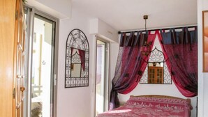 A bedroom with a wooden bed, a window with decorative ironwork, and a view of the outside. - Grand Pavois by Interhome (Mimizan)