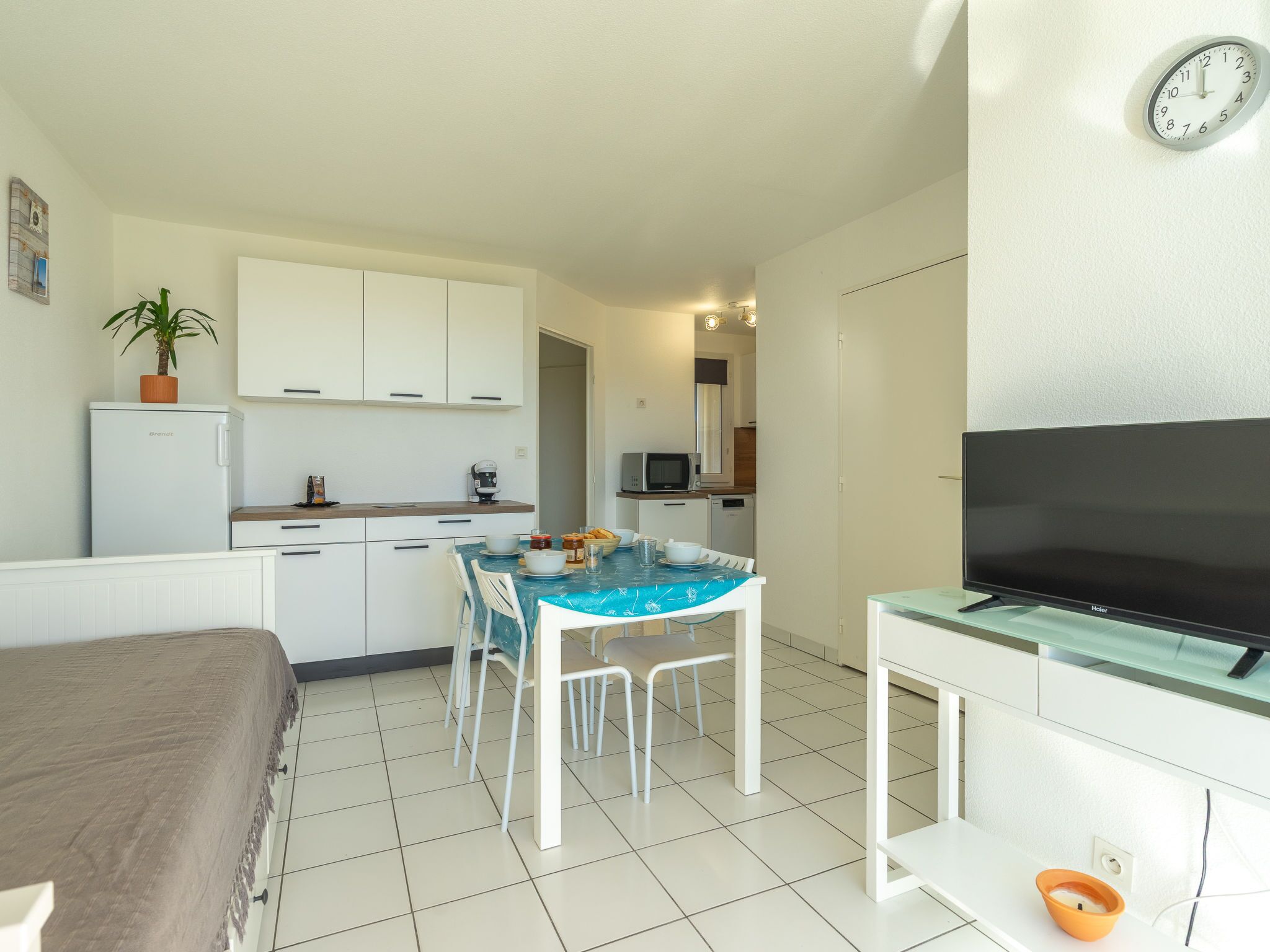 A compact living space with a kitchenette, a dining area, a TV, and a bed.