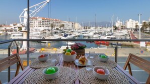 Een eettafel met uitzicht op een jachthaven en gebouwen op de achtergrond.